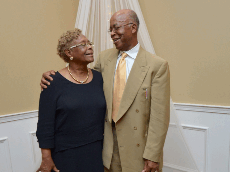 Elderly couple smiling and embracing at formal event