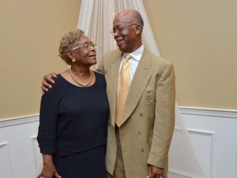 Elderly couple smiling and embracing at formal event