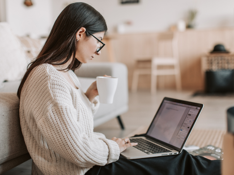 Woman working on laptop at home with coffee, representing beginner content creator preparing a media kit.