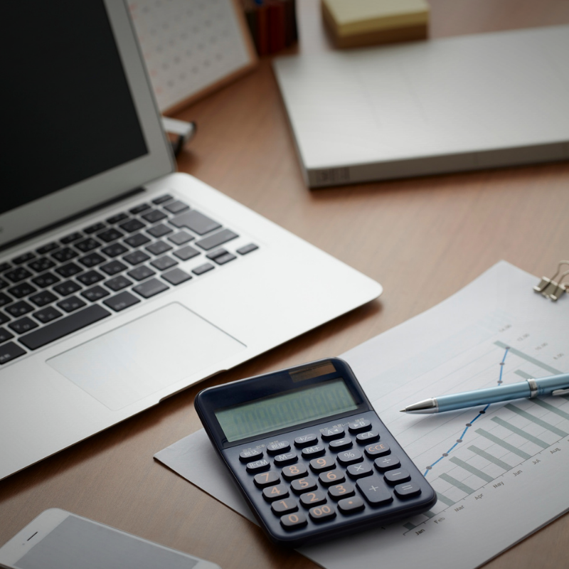 Flat lay of laptop, calculator, and graph chart representing clarity, confidence, and organization at work