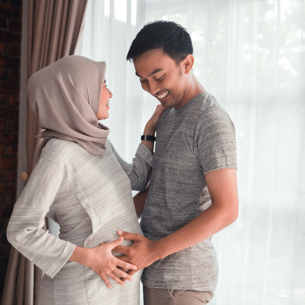 Expectant couple smiling and embracing while preparing for their future together