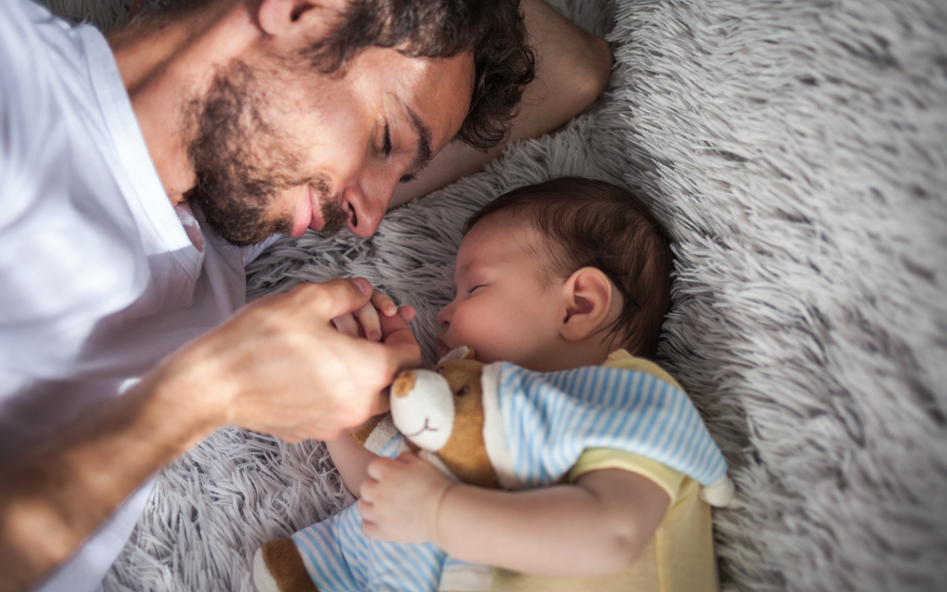 Father lying beside infant child, illustrating early bonding and involvement